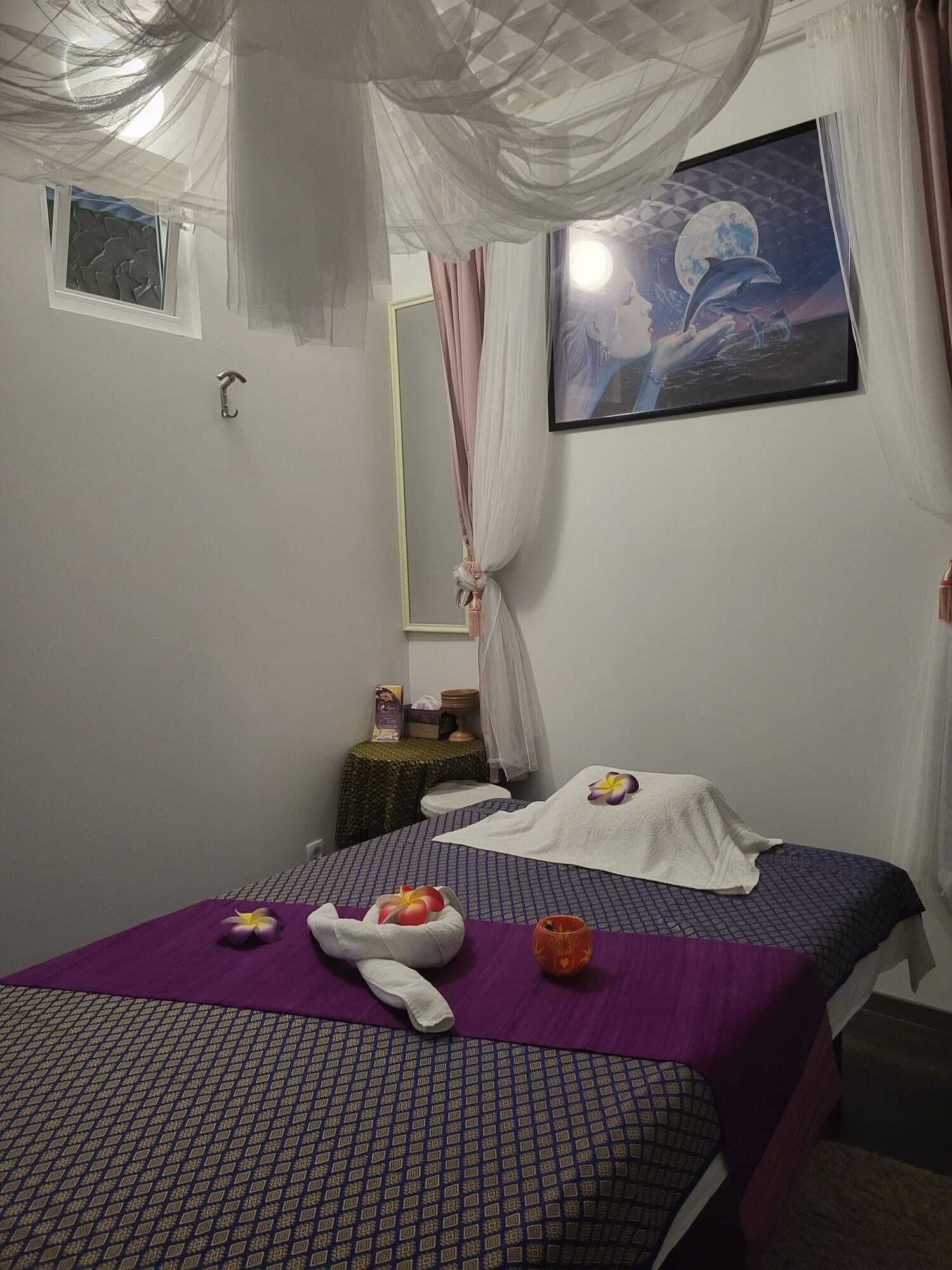 Ruhiges Massagezimmer mit dekoriertem Massagetisch, weißen Handtüchern, Blüten und entspannender Atmosphäre