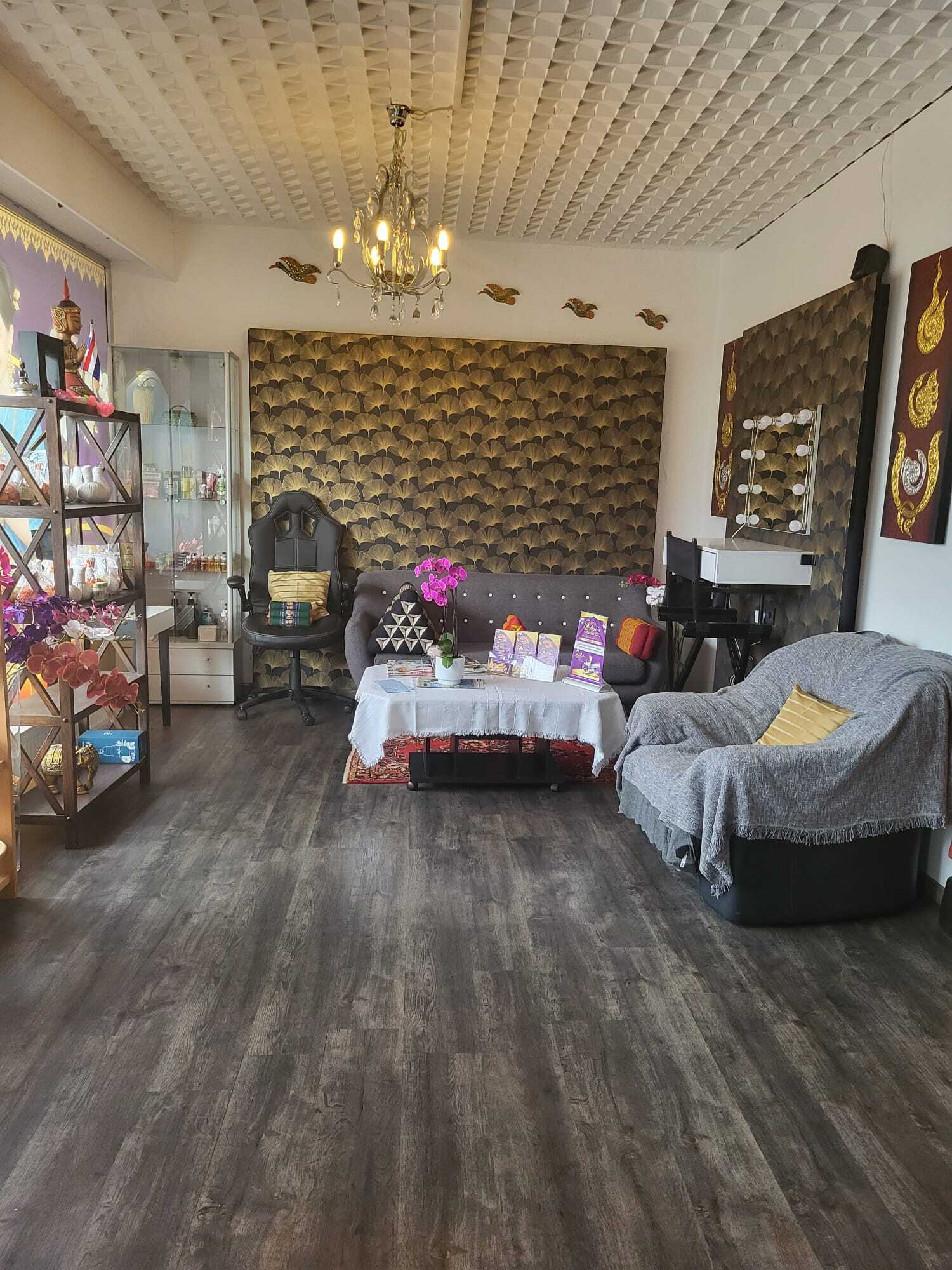 Stilvoll eingerichtetes Thai Massage Warteraum mit violettem weichen Sofas, Blumen und Kerzen für Entspannung